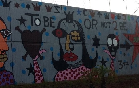 Detail of Walls of Hope: a heart with crossbones, a crowned figure and a skull, beneath the words TO BE OR NOT 2 BE