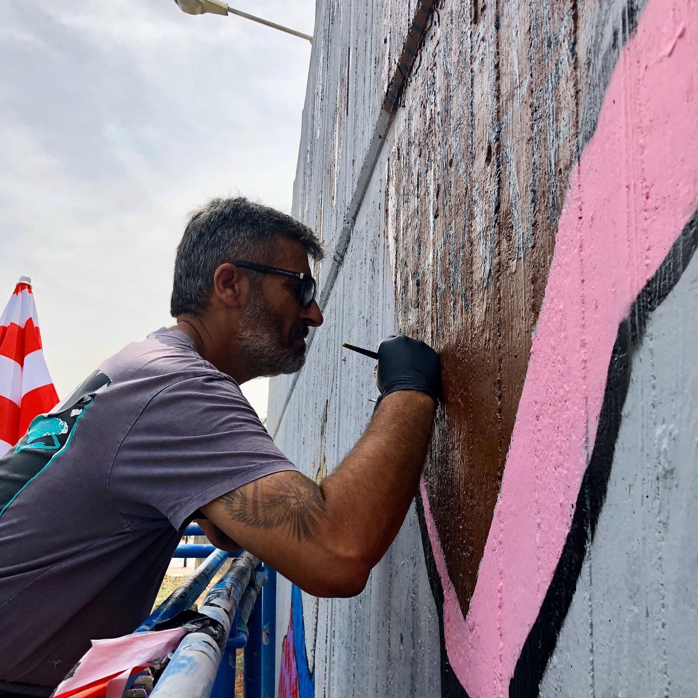 Bazooka Joe painting the pink and gray section of Walls of Hope
