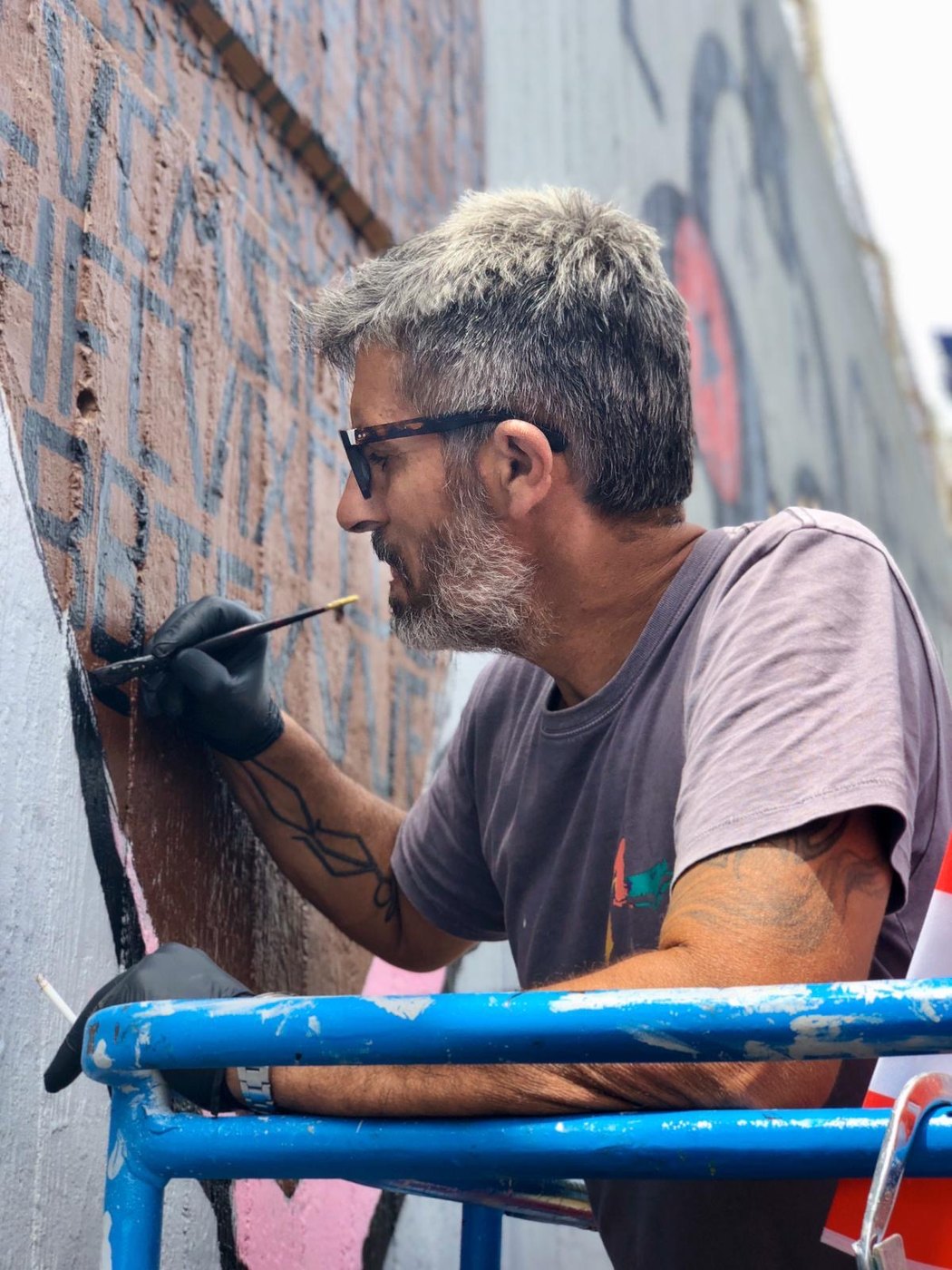 Bazooka Joe painting Walls of Hope from a scaffold